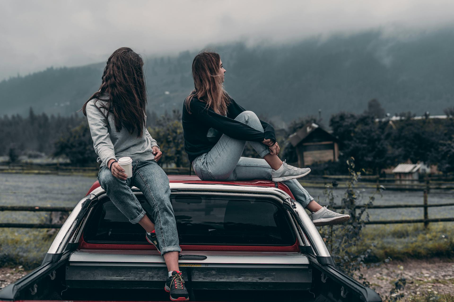 Two people sitting on a car roof with a scenic background